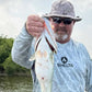 picture of a man holding a bass he caught while wearing a shelts sun hat and sun shirt.