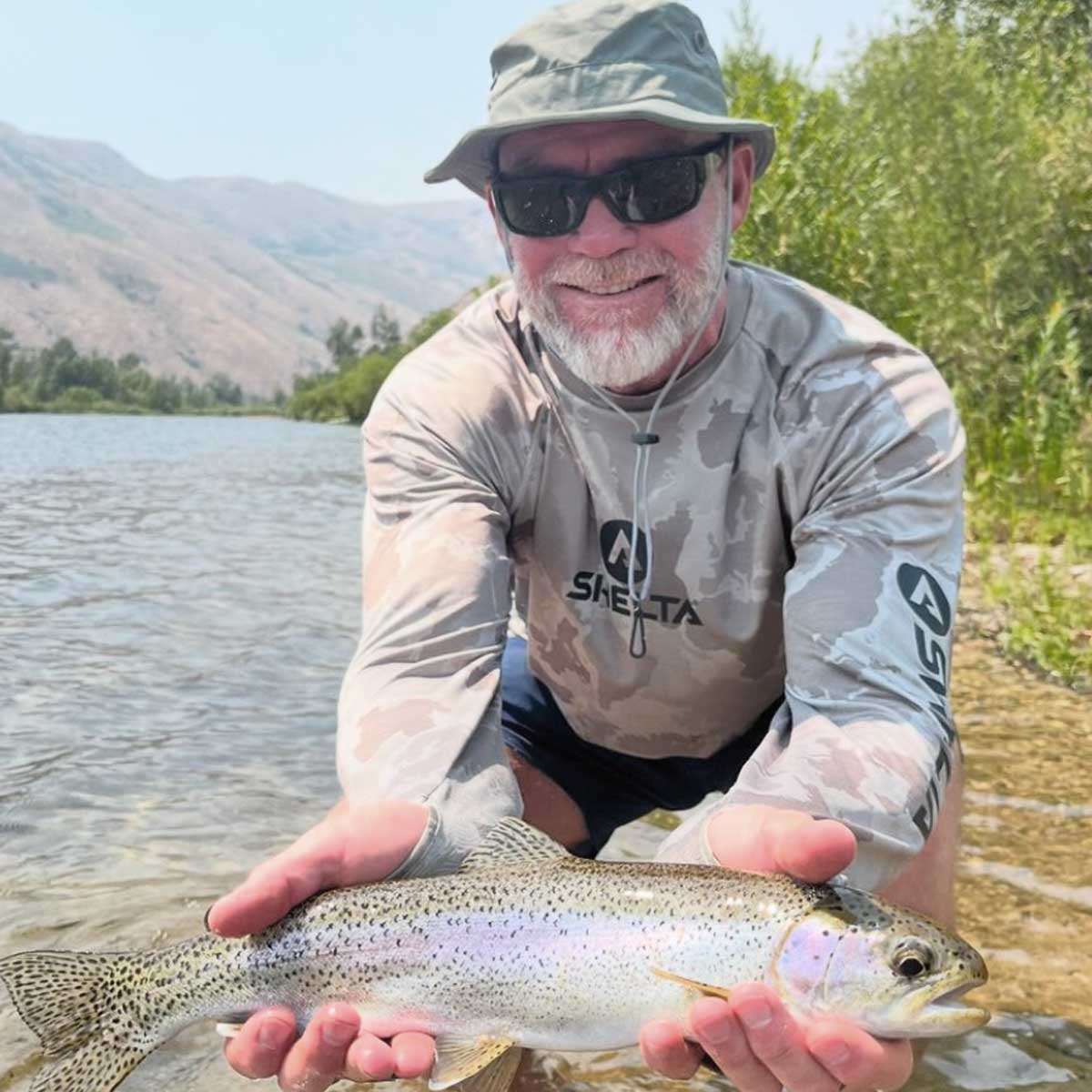 Picture of Man holding  fish while wearing shelta Sun shirt and Sun hat